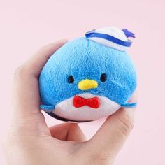 a hand holding a blue stuffed animal with a bow tie on it's head