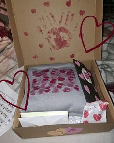 an open box with hearts and handprints on the inside, sitting on a bed