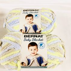 two balls of bernat baby blanket yarn in yellow, blue and white colors on top of each other