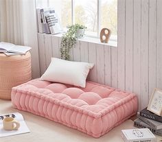 a pink futon bed sitting on top of a white floor next to a window