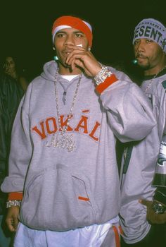 two young men standing next to each other in front of a crowd wearing hoodies