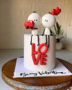 a cake decorated with two people in love on top of a wooden table next to a potted plant