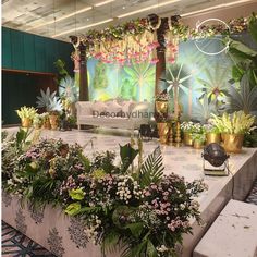 a table with flowers and greenery on it in front of a stage set up for an event