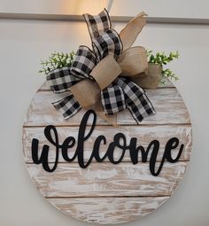 a welcome sign hanging on the wall with burlocks and greenery around it