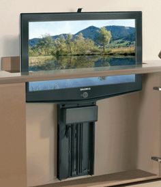 a flat screen tv sitting on top of a wooden shelf