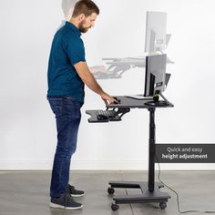 a man standing in front of a desk with a monitor and keyboard attached to it