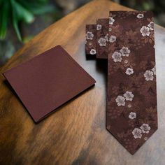 The Perfect Floral Silk Necktie: Timeless Elegance and Versatility Discover the elegance and versatility of our silk necktie, adorned with a charming small flowers pattern in shades of brown and white. Available in two widths—3.25 inches for a traditional look or 2.5 inches for a modern, slim fit—this necktie caters to every style preference. With two length options, 60 inches (regular) and 63 inches (extra-long), you can find the perfect fit for any occasion. Pair your purchase with a matching Elegant Floral Print Accessories For Black Tie, Elegant Floral Print Ties For Gifts, Elegant Floral Print Ties As A Gift, Elegant Floral Print Ties As Gift, Classic Floral Print Tie For Gift, Classic Floral Print Tie As A Gift, Classic Floral Print Ties As Gifts, Elegant Brown Suit And Tie Accessories With Pocket Square, Classic Brown Suit And Tie Accessories As Gift