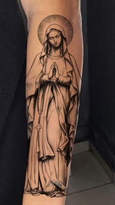 a woman's arm with a tattoo of the virgin mary in black and white