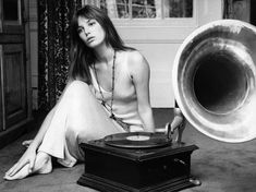 a woman sitting on the floor next to a record player