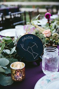 the table is set with flowers, candles and astro signs on it's plates