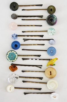 several different types of sewing needles are arranged on a white surface with buttons and thread spools