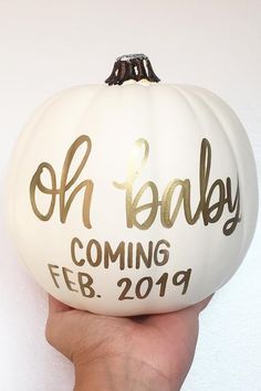 a person holding up a white pumpkin with the words oh baby coming feb 29th on it