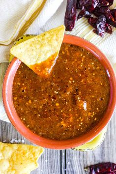 salsa in a bowl with tortilla chips on the side and red peppers next to it