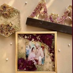 two framed photos are sitting next to each other on a table with beads and flowers