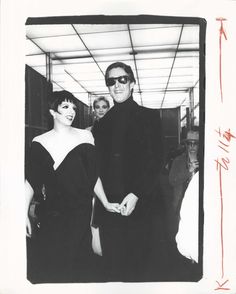 an old black and white photo of two people standing next to each other with sunglasses on