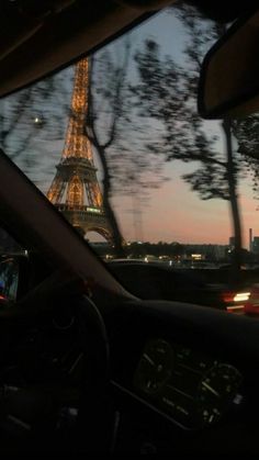 the eiffel tower is lit up at night as seen from inside a car