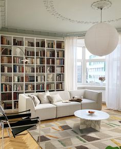 a living room filled with furniture and bookshelves covered in lots of bookcases