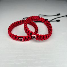 two red bracelets sitting on top of a white table