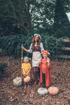 a woman and two children dressed up as scarecrows with pumpkins on the ground