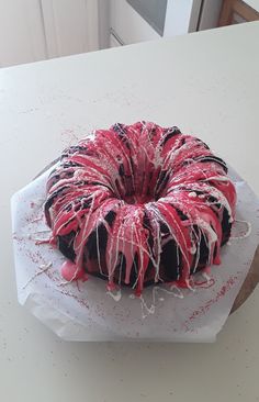 a bundt cake with sprinkles and red icing sitting on top of a white table