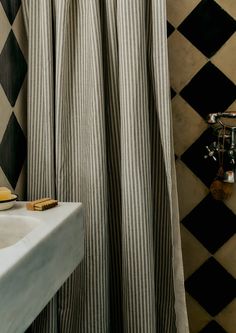 a black and white checkered shower curtain next to a sink with soap on it