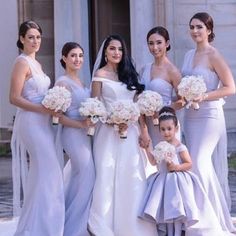 a group of women standing next to each other wearing dresses and holding bouquets in their hands