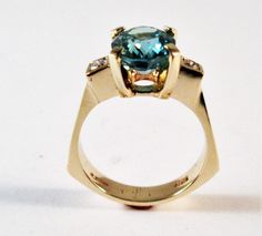 A 14kt yellow gold original designer ring Center stone is a 10x8 mm oval Swiss blue topaz Side diamonds are two round 2.5mm si1 g/h color tdw .14cts Can be ordered in white gold, yellow gold, rose gold, and platinum Comes in all sizes Comes in a beautiful box 100% MONEY BACK GUARANTEE Modern Topaz Ring With Center Stone In Yellow Gold, Modern Yellow Gold Topaz Ring With Center Stone, Modern Topaz Ring With Gemstone Accents, Modern Topaz Ring With Gemstone Accents For Anniversary, Modern Oval Topaz Ring With Prong Setting, Swiss Blue Topaz Ring, Mystic Topaz, Round Rings, Swiss Blue Topaz