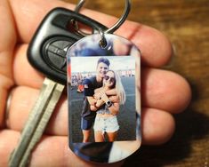 a person holding a keychain with a photo on it and a car key