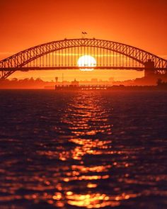 the sun is setting behind an arched bridge