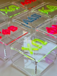 four clear acrylic boxes with neon colored letters on them and the word love spelled inside