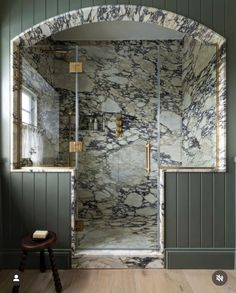 a walk in shower sitting next to a wooden floor covered in green and white marble