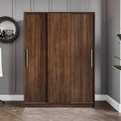 a room with a chair, mirror and two wooden closets in the middle of it