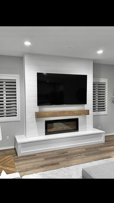 a large flat screen tv mounted on the wall above a fireplace in a living room