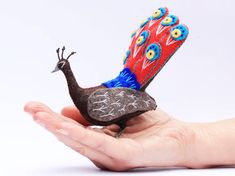 a hand holding a small bird made out of felt