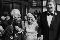 black and white photograph of an older couple walking down the street with other people behind them