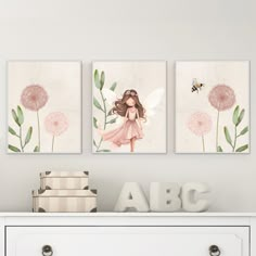 three flower paintings on the wall above a dresser with books and a toy in front of it