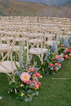 rows of wooden chairs with flower arrangements on the back are lined up for an outdoor ceremony