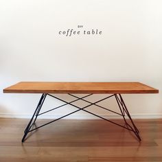 a wooden table sitting on top of a hard wood floor next to a white wall