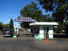 a car is parked in front of a small hamburger shop on the side of the road