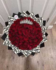 a bouquet of red roses with a crown on top