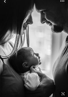 a man and woman holding a baby in their arms