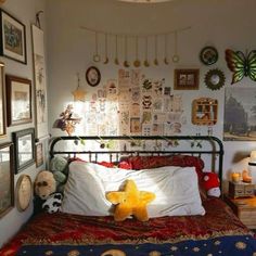 a bedroom with many pictures on the wall and a teddy bear laying on the bed