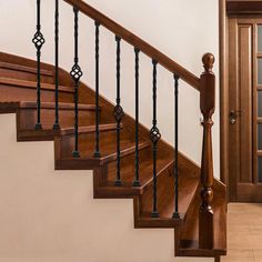 a wooden stair case with wrought iron balconies and handrails in an empty room