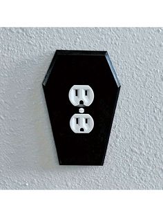 a black and white hexagonal outlet on the wall with two outlets in it