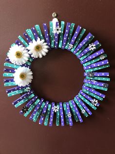 a wreath made out of popsicle sticks with daisies in the middle and snowflakes on each side