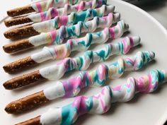 there are many different types of marshmallows on the white plate with candy sticks