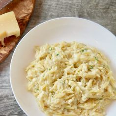 a white plate topped with macaroni and cheese next to a wooden cutting board