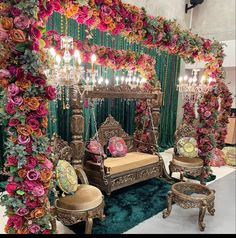 an elaborately decorated room with flowers and chandeliers on the wall, along with couches and chairs