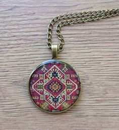 a necklace with a colorful design on it sitting on a wooden table next to a chain