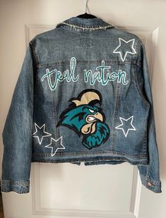 "Coastal Carolina University denim jacket designed and painted just for you!! *These are made to order. I currently do not have any completed of this design in stock.  Please include the following information when purchasing: 1. Design idea (if different than pictured) 2. Size of jacket  3. Date needed by (please note I have a 3-4 week processing time at the moment. if you need the jacket sooner please reach out to confirm with me that I can have it processed by the date you need it before purchasing) 4. Optional: any other preferences (wash of jacket , distressing, etc.).  If no preferences are given I typically use Universal Thread or Wild Fable brand jackets from target in a medium wash. Want to add a name / phrase or any other customization? Please include in the notes / comments secti Trendy Denim Jacket For Fall Customization, Trendy Cotton Denim Jacket With Custom Artwork, Casual Cotton Outerwear With Hand Painted Details, Casual Cotton Hand Painted Outerwear, Casual Hand Painted Blue Outerwear, Casual Hand Painted Cotton Outerwear, Spring Casual Denim Jacket With Custom Artwork, Casual Spring Denim Jacket With Custom Artwork, Casual Blue Denim Jacket With Custom Artwork